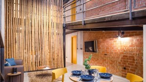 A modern dining area with a round table set for four, yellow chairs, and a bamboo wall. - Art Loft 05 'The Mechanic' in Valencia (València)