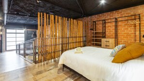 A modern bedroom with a large bed, a bamboo wall, and a brick wall. - Art Loft 05 'The Mechanic' in Valencia (València)
