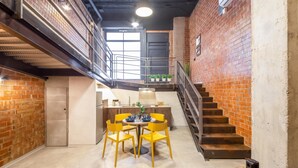 A modern interior with a staircase, a dining area with yellow chairs, and a kitchen in the background. - Art Loft 05 'The Mechanic' in Valencia (València)