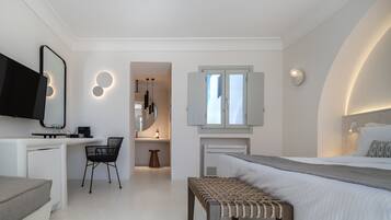 Una camera da letto moderna con un letto, un comodino, una TV e un piccolo angolo relax.