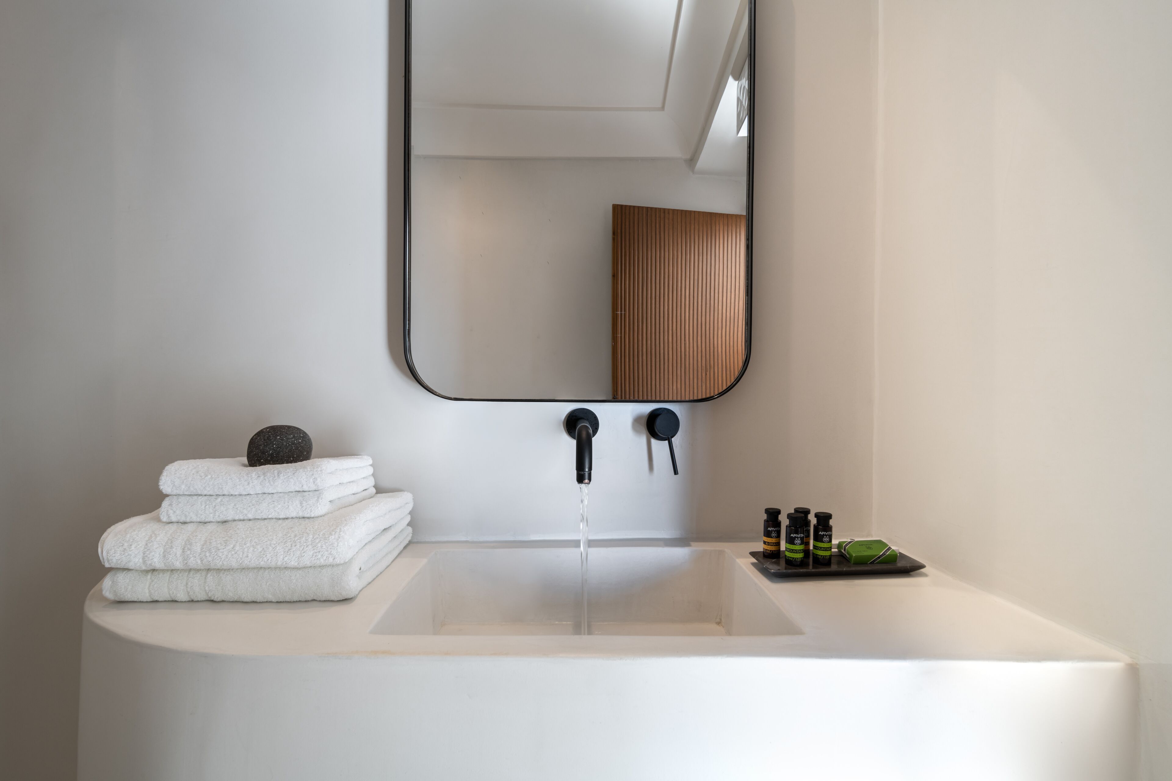 Un baño moderno con un espejo grande, un lavamanos y toallas ordenadas.