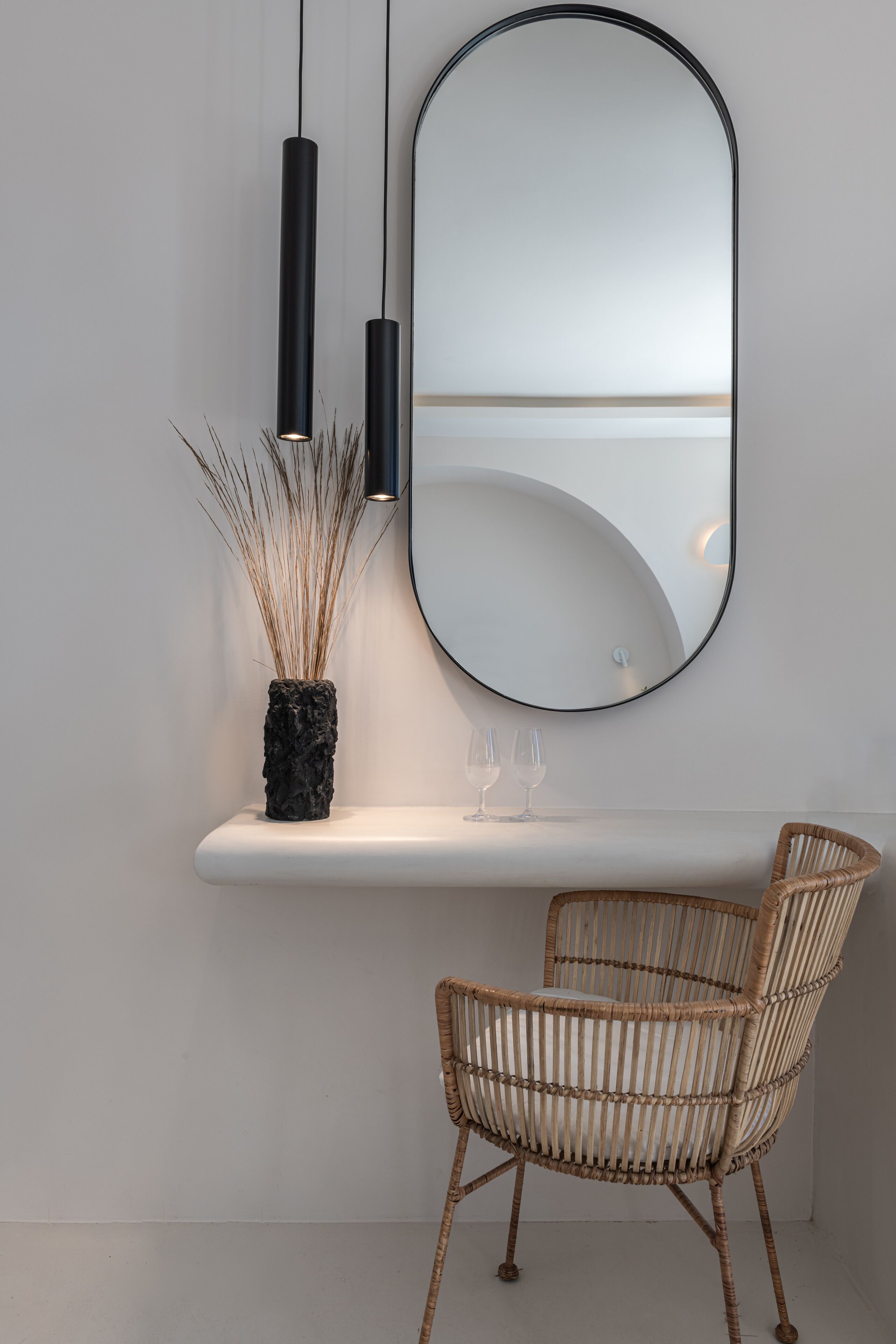 A modern bathroom with a white vanity, a large mirror, and two black pendant lights.
