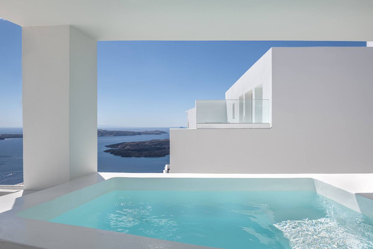 A modern pool area with a clear view of the sea and rocky coastline.
