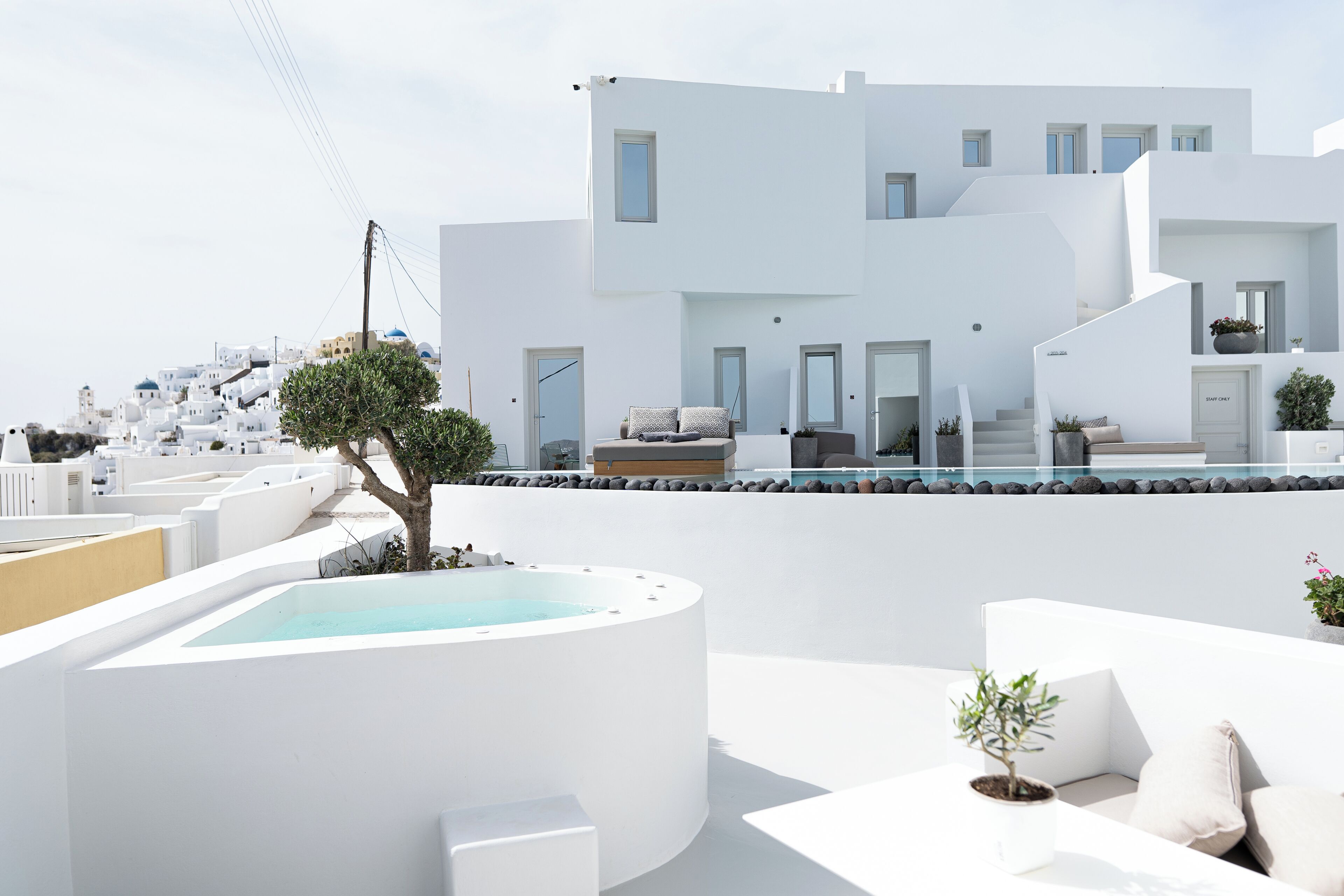 A modern white building with a rooftop pool and outdoor seating area.