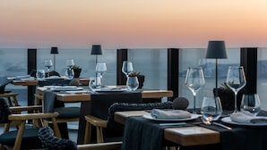A restaurant with tables set for dining, each with wine glasses, plates, and cutlery. - Akra Suites & Spa (Santorini)