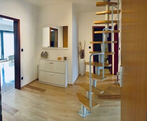 Stylish interior with a minimalist design, featuring a wall-mounted cabinet, wooden staircase, and decorative branches.