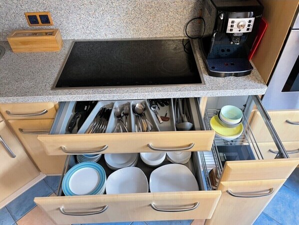 A kitchen with a granite countertop, a built-in stove, and a dish rack with plates and utensils. - Modern Apartment with a Terrace, 15 Minutes from Downtown, NETFLIX (Dinslaken)