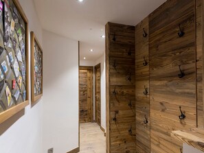 A hallway with wooden paneling and black hooks on the walls.