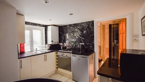 A compact kitchen with a black countertop, white cabinets, a dishwasher, and a stove. - Old Compton (London)