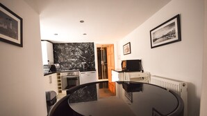A compact kitchen with modern appliances, a dining table, and a black marble backsplash. - Old Compton (London)