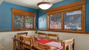 A dining area with a wooden table and chairs, a red placemat, and two windows with wooden frames. - Relaxed Comfort in a Prime Location – The Pines at Ore House! (Steamboat Springs)