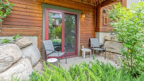 A wooden cabin with a glass door, two chairs, and a small table outside. - Relaxed Comfort in a Prime Location – The Pines at Ore House! (Steamboat Springs)
