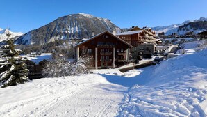 A snow-covered mountain with a wooden lodge and several buildings in the background. - Spacious 3-bedroom, ski-in/ski-out with parking and wifi (Courchevel 1550)