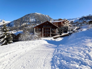 Ein schneebedeckter Berg mit einer Holzhütte und mehreren Gebäuden im Hintergrund.