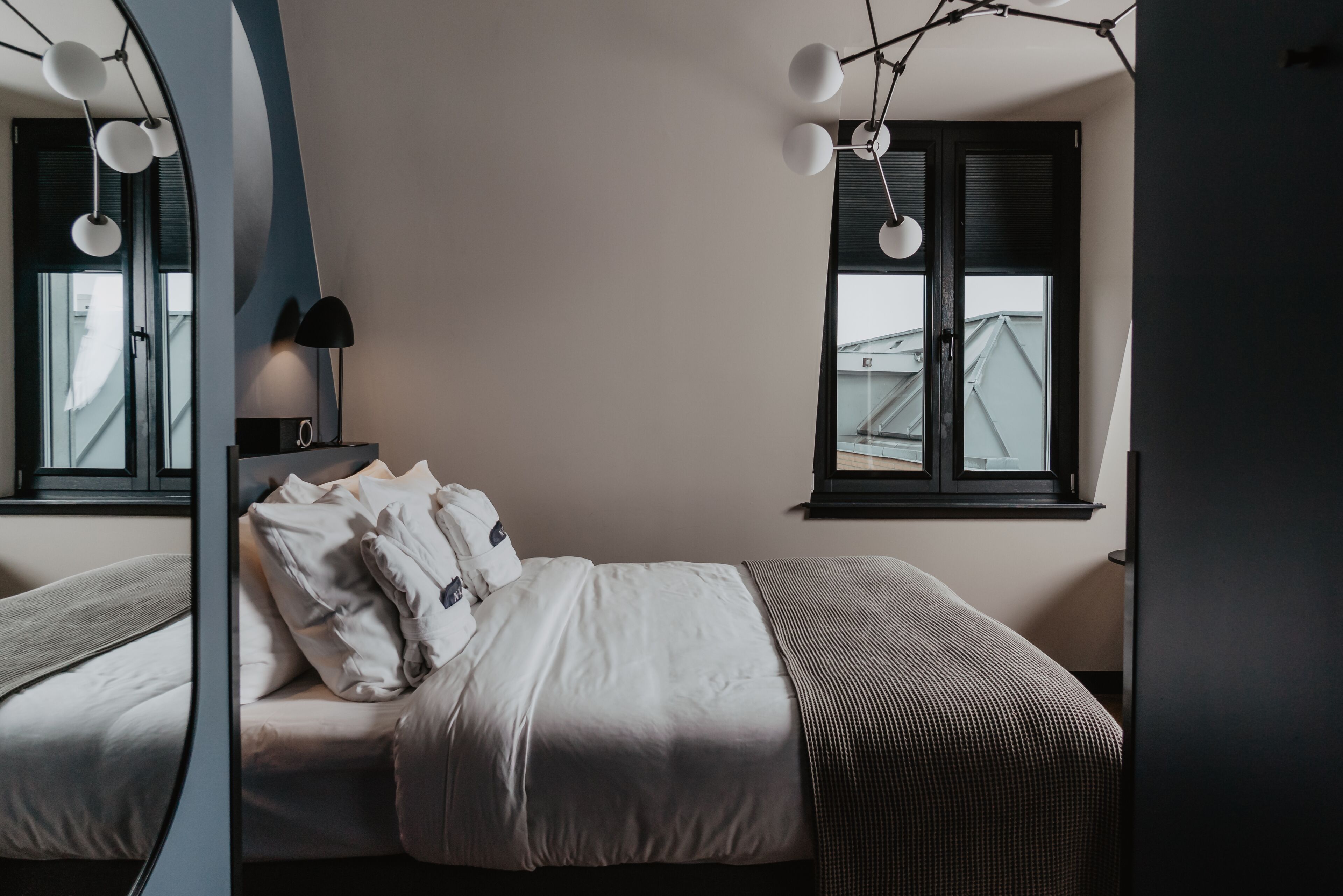 Een slaapkamer met een bed, een nachtkastje met een lamp en een raam met zonwering.