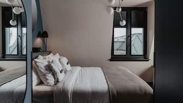Een slaapkamer met een bed, een nachtkastje met een lamp en een raam met zonwering.