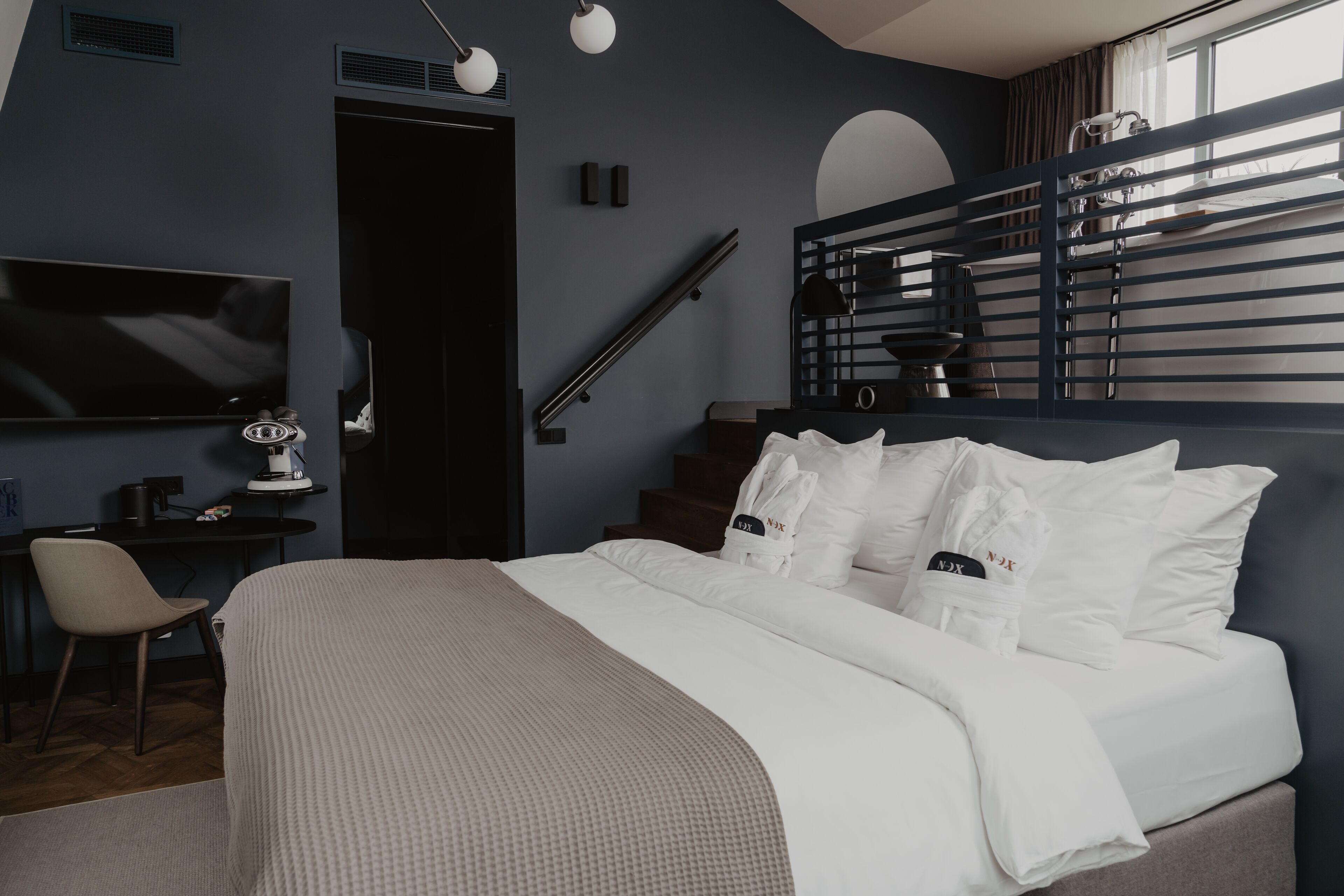 Une chambre moderne avec un lit, une table de chevet, une lampe et un téléviseur fixé au mur.