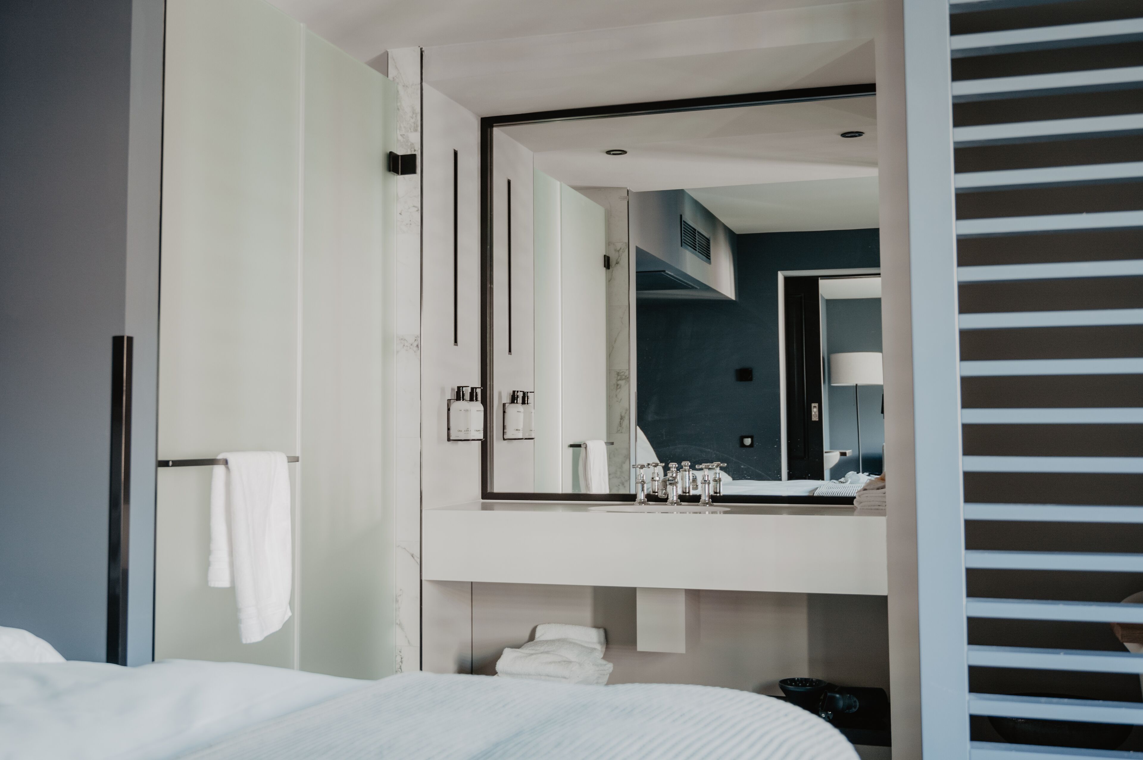 Una camera d'hotel moderna con un letto grande, bagno con specchio e vista sulla città.