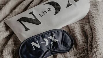 Cuscino e mascherina per gli occhi con la scritta "N the NX", posti su una superficie in tessuto strutturato.
