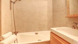 Une salle de bain avec une baignoire, un lavabo et un miroir.