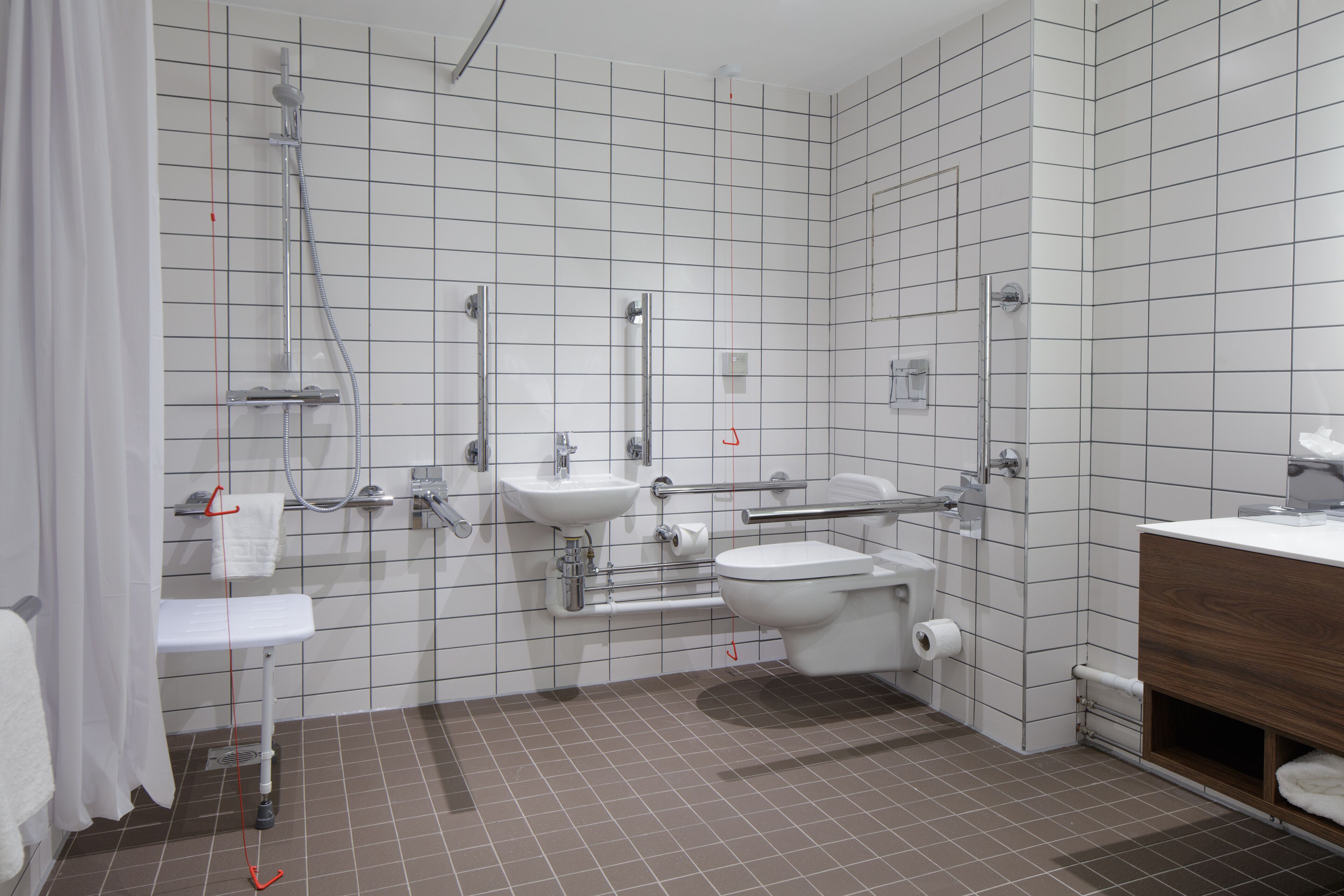 Een moderne badkamer met douche, wastafel, toilet en een houten wastafelmeubel.
