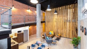 A modern interior with exposed brick walls, a kitchen area, a dining space with a table set for two, and a seating area with a sofa and chairs. - Art Loft 06 'Travelling Light' in Valencia (València)