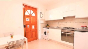 A compact kitchen with a washing machine, oven, and white cabinets. - Sorrento Historical Center (Sorrento)