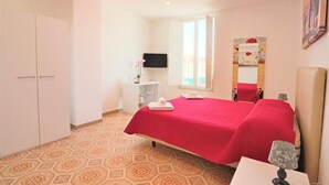 A bedroom with two beds, a TV, a window, and a mirror. - Sorrento Historical Center (Sorrento)