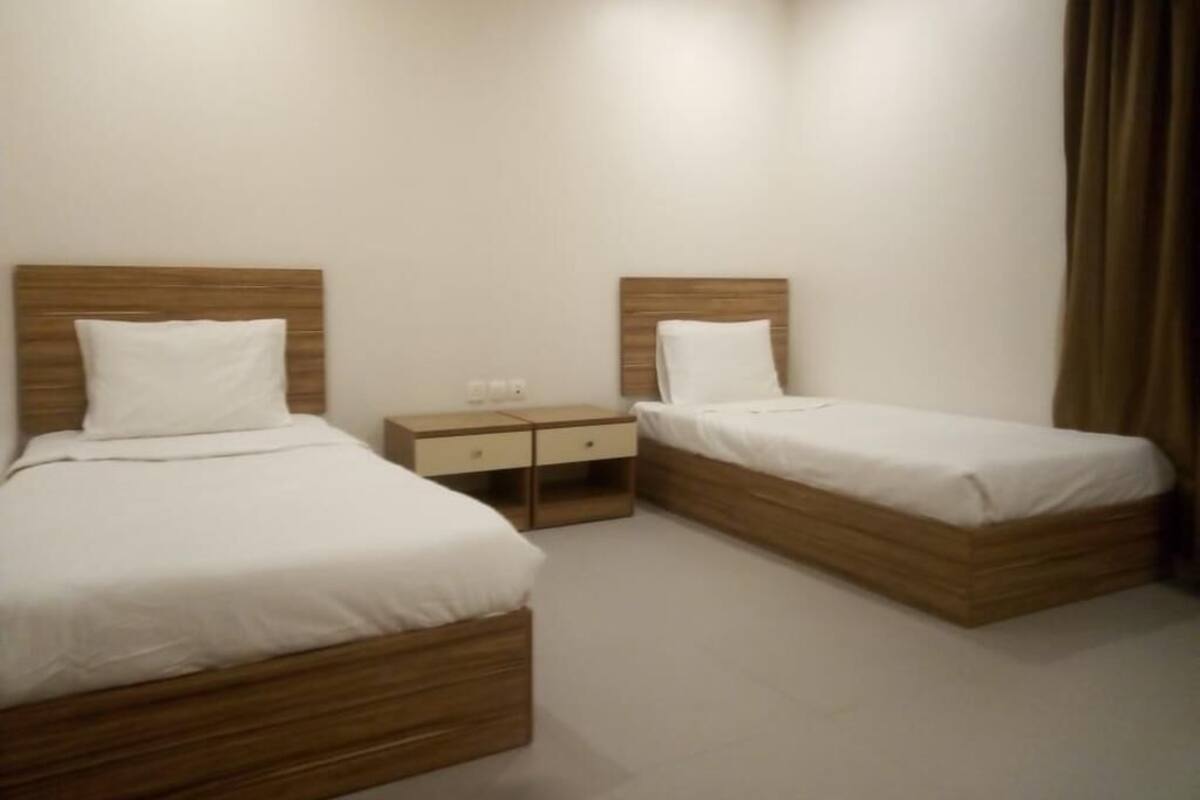 Une chambre d’hôtel avec deux lits simples, une table de chevet et une petite table.