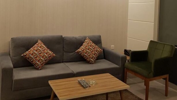 A modern living room with a grey sofa, two patterned cushions, a wooden coffee table, and a green armchair.