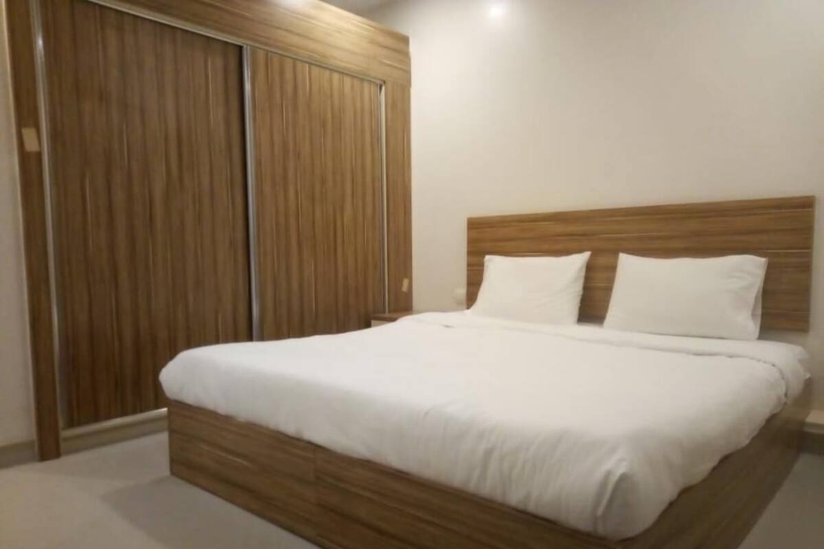 Une chambre à coucher avec un lit en bois, du linge de lit blanc et une armoire en bois.
