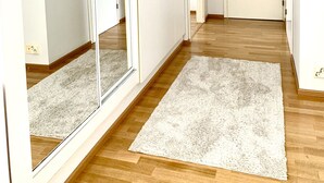 A hallway with wooden flooring, a white carpet, and a white door at the end. - City Home Finland Laukontori (Tampere)