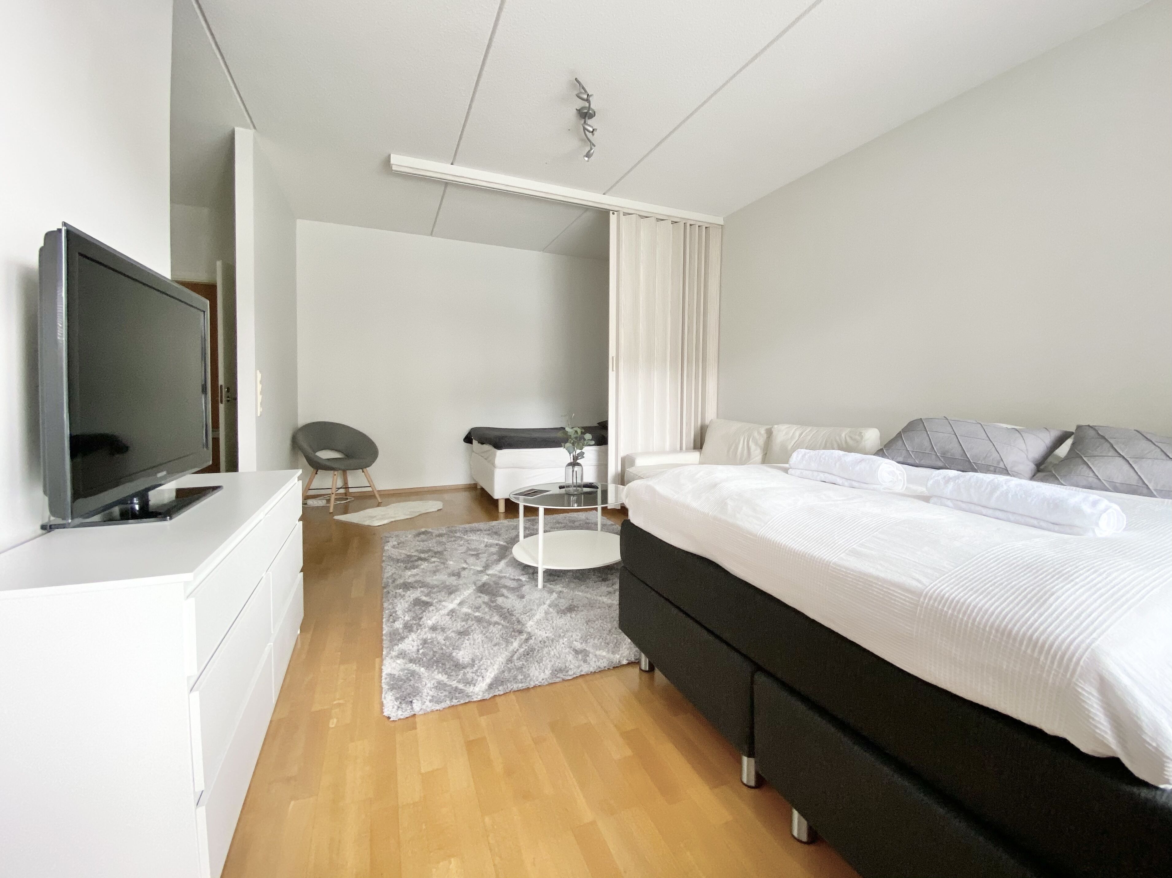 Un dormitorio moderno con una cama grande, un televisor, un escritorio y una silla.