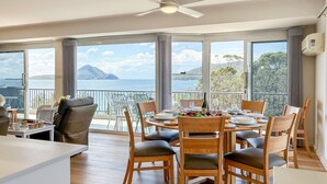 A dining area with a view of the sea and mountains, featuring a table set for four with chairs. - Albacore 7, 12 Ondine Close, Waterfront Unit with (Nelson Bay)