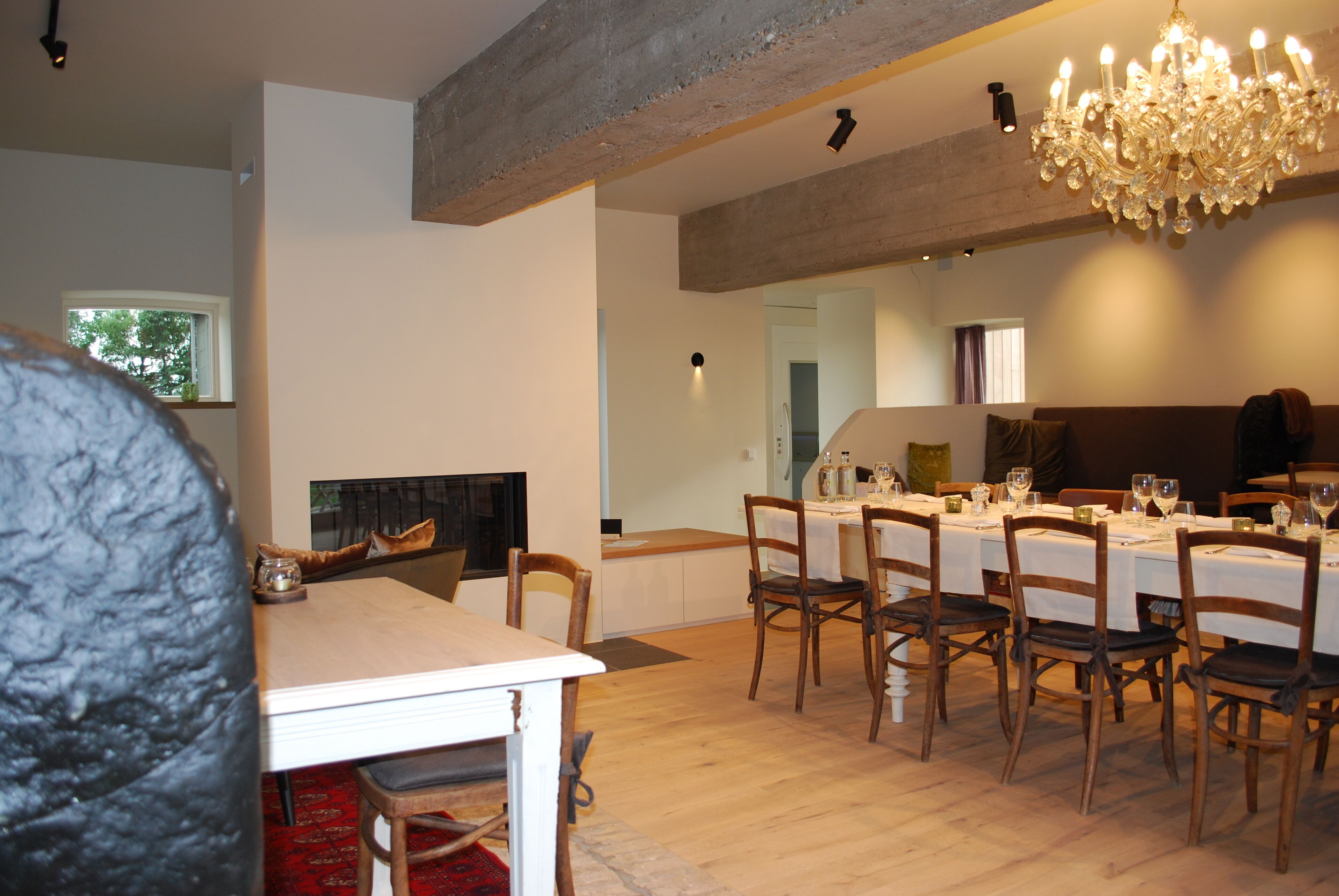 A dining area with a long table set for six, wooden chairs, and a chandelier.