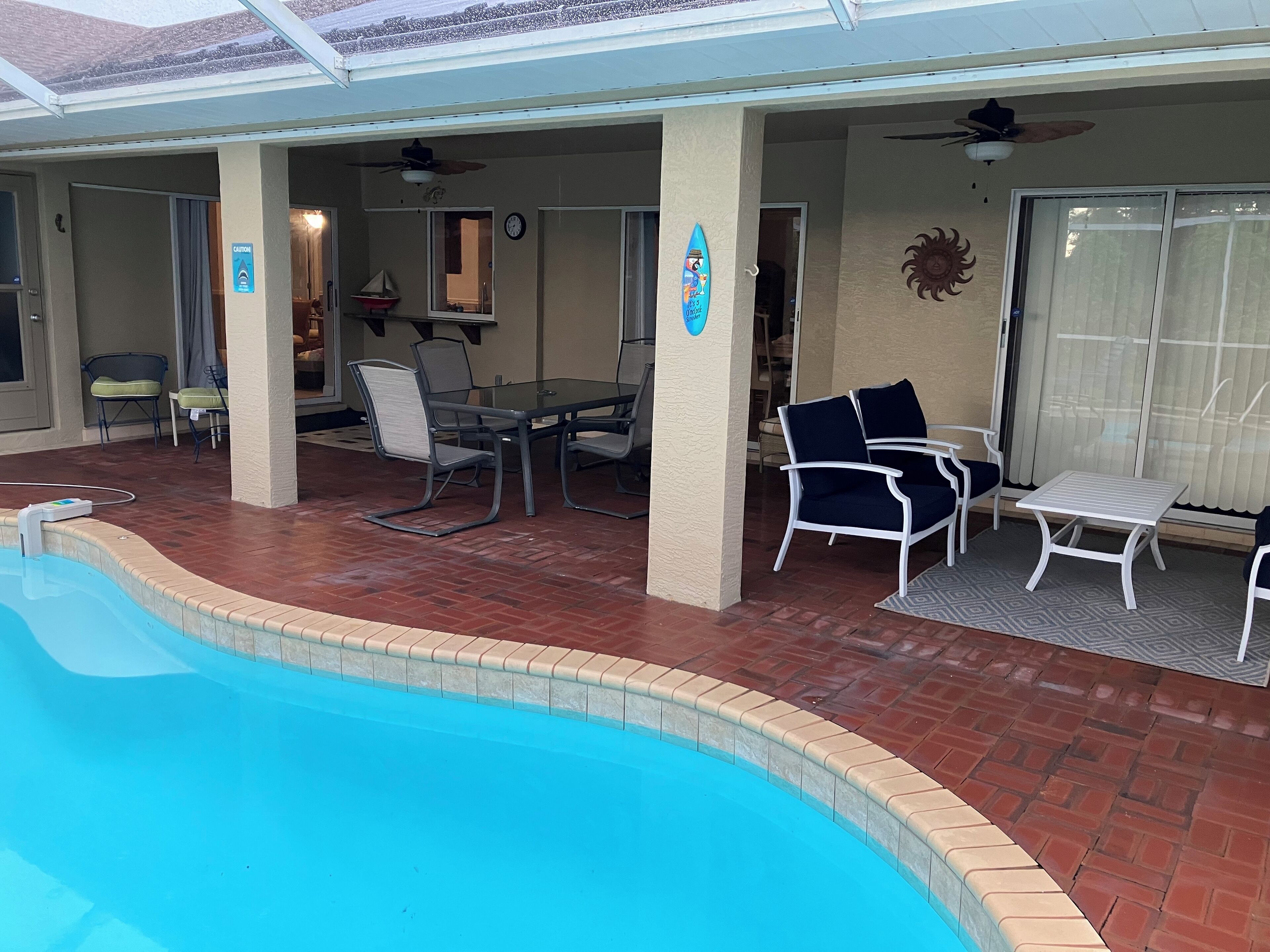 A covered outdoor area with a pool, patio furniture, and a dining table.