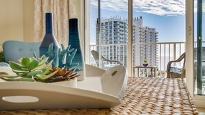 Un balcon doté d'un plancher en osier, d'une chaise blanche, d'une petite table avec une plante et de deux vases décoratifs.