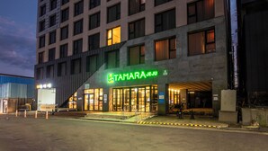 A modern hotel with a prominent entrance, large windows, and a well-lit facade. - Tamara Jeju (Seogwipo)