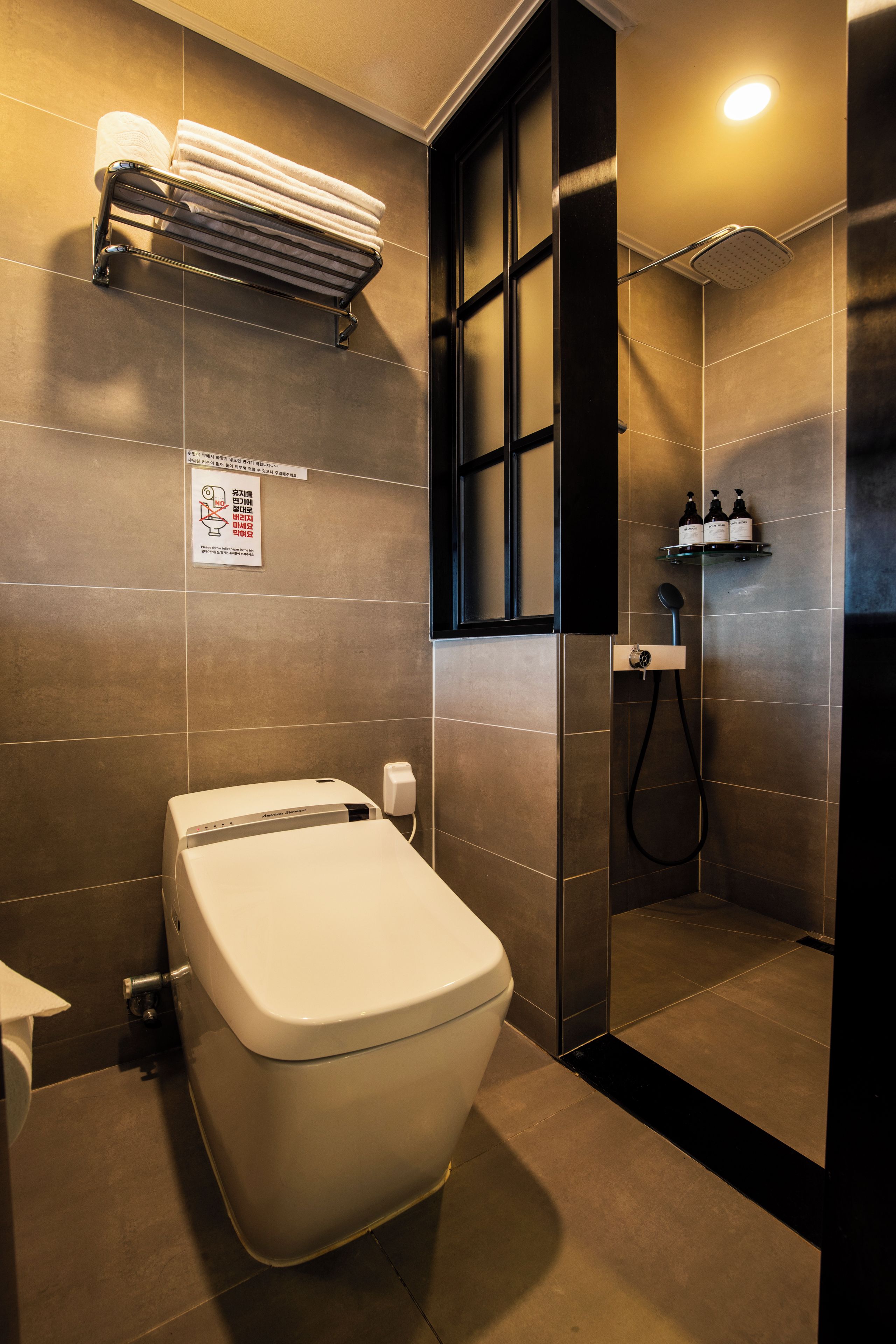 Un baño moderno con inodoro, zona de ducha y perchero.