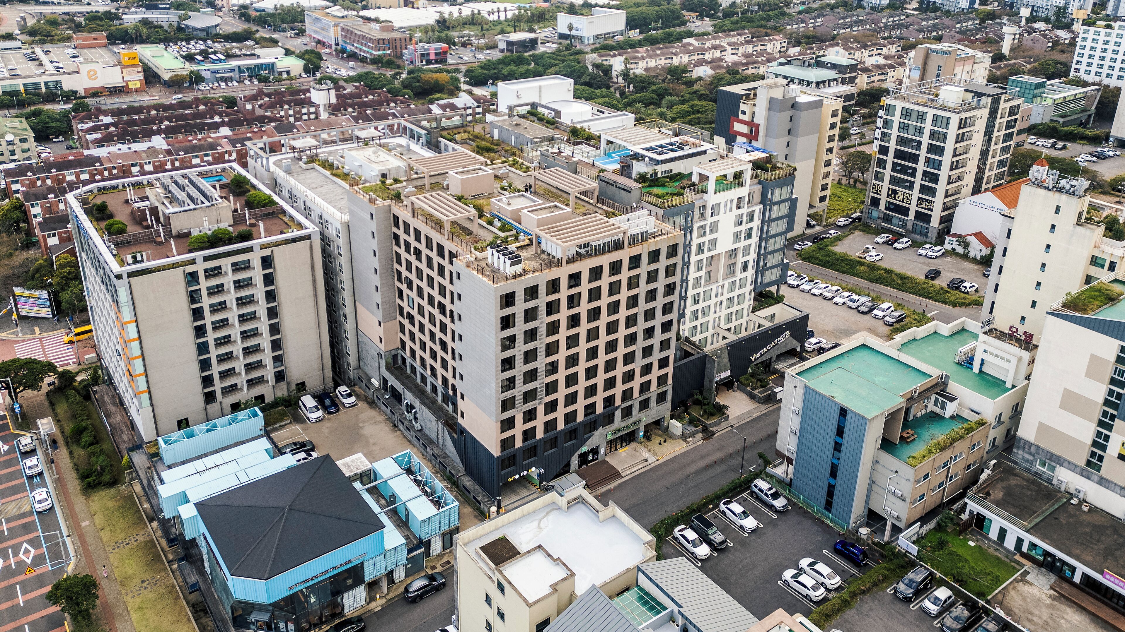 A high-rise building with multiple floors, a rooftop garden, and a parking lot.