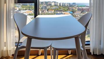 A dining area with a table and chairs, large windows with a city view, and wooden flooring.