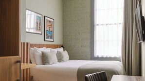 Una habitación de hotel con una cama, cabecera de madera, una mesa y un televisor.