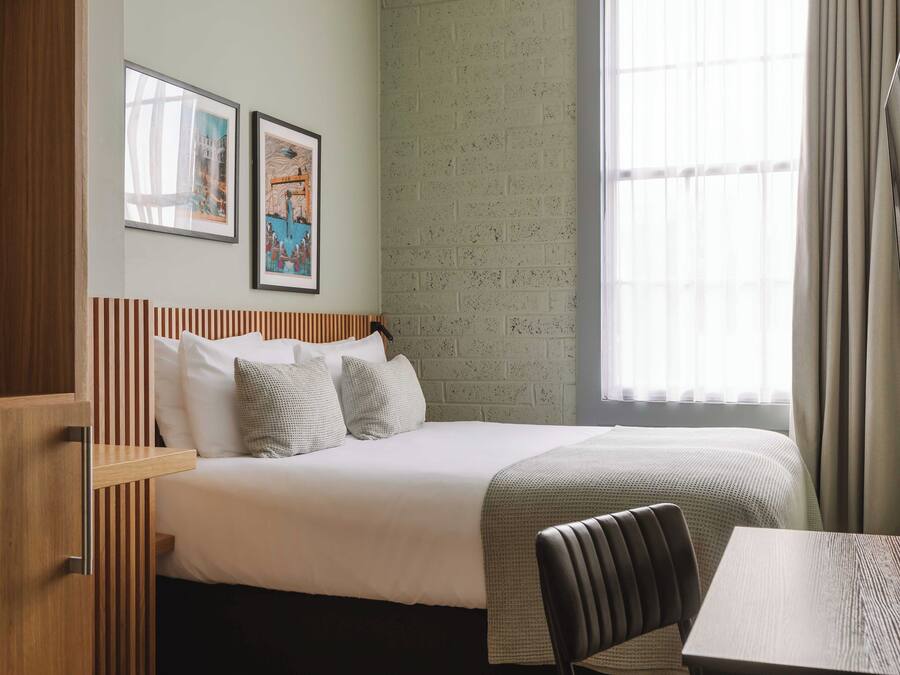 Ein Hotelzimmer mit Bett, Holz-Kopfteil, Tisch und Fernseher.