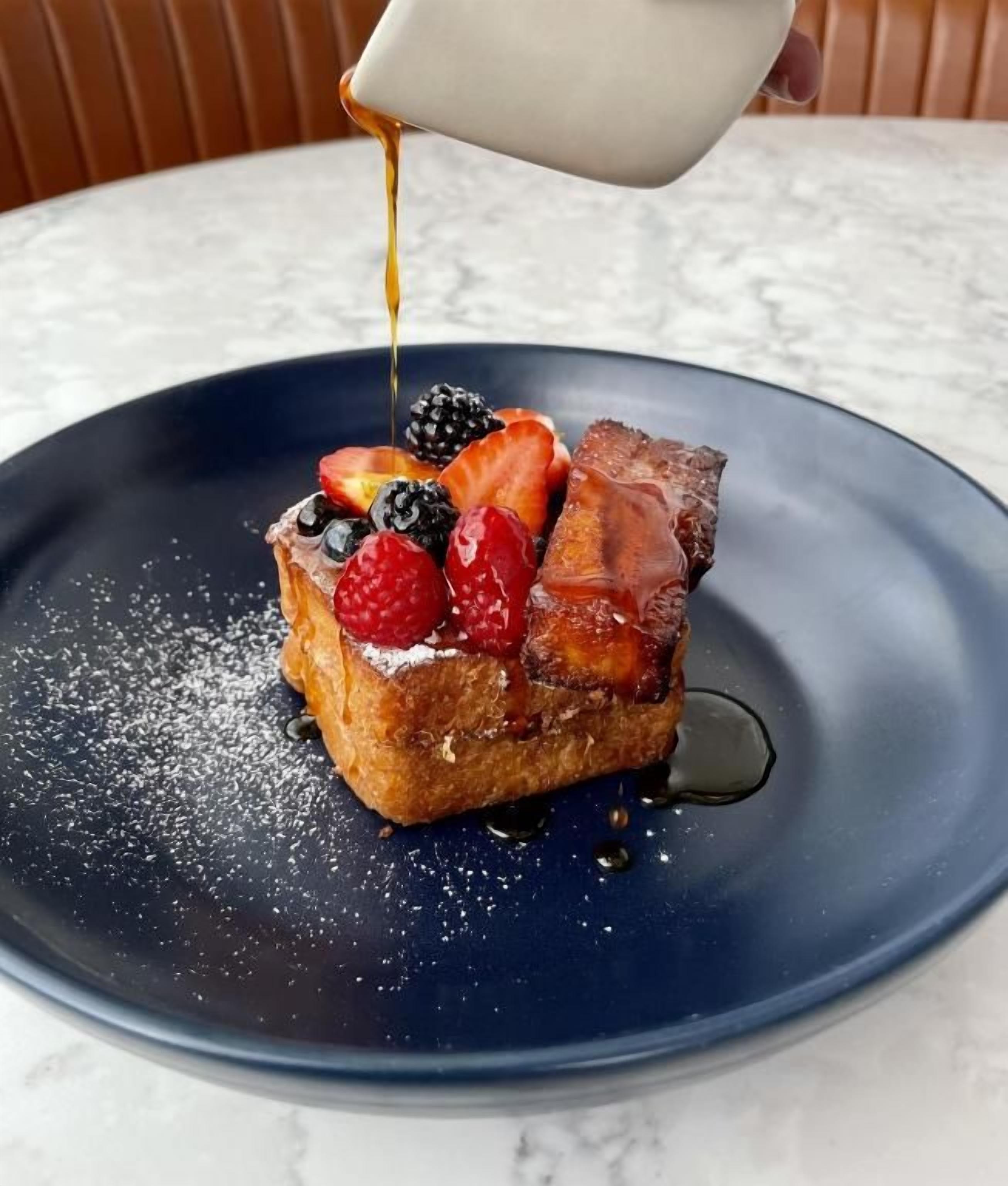 Un postre en un plato con almíbar vertiéndose sobre él.