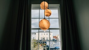 Una ventana con tres lámparas colgantes esféricas suspendidas del techo.