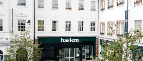A building with a storefront labeled "haslem" featuring a modern entrance with glass doors and a green awning.