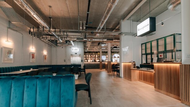 Un restaurante moderno con asientos color turquesa, un mostrador de recepción y conductos expuestos.