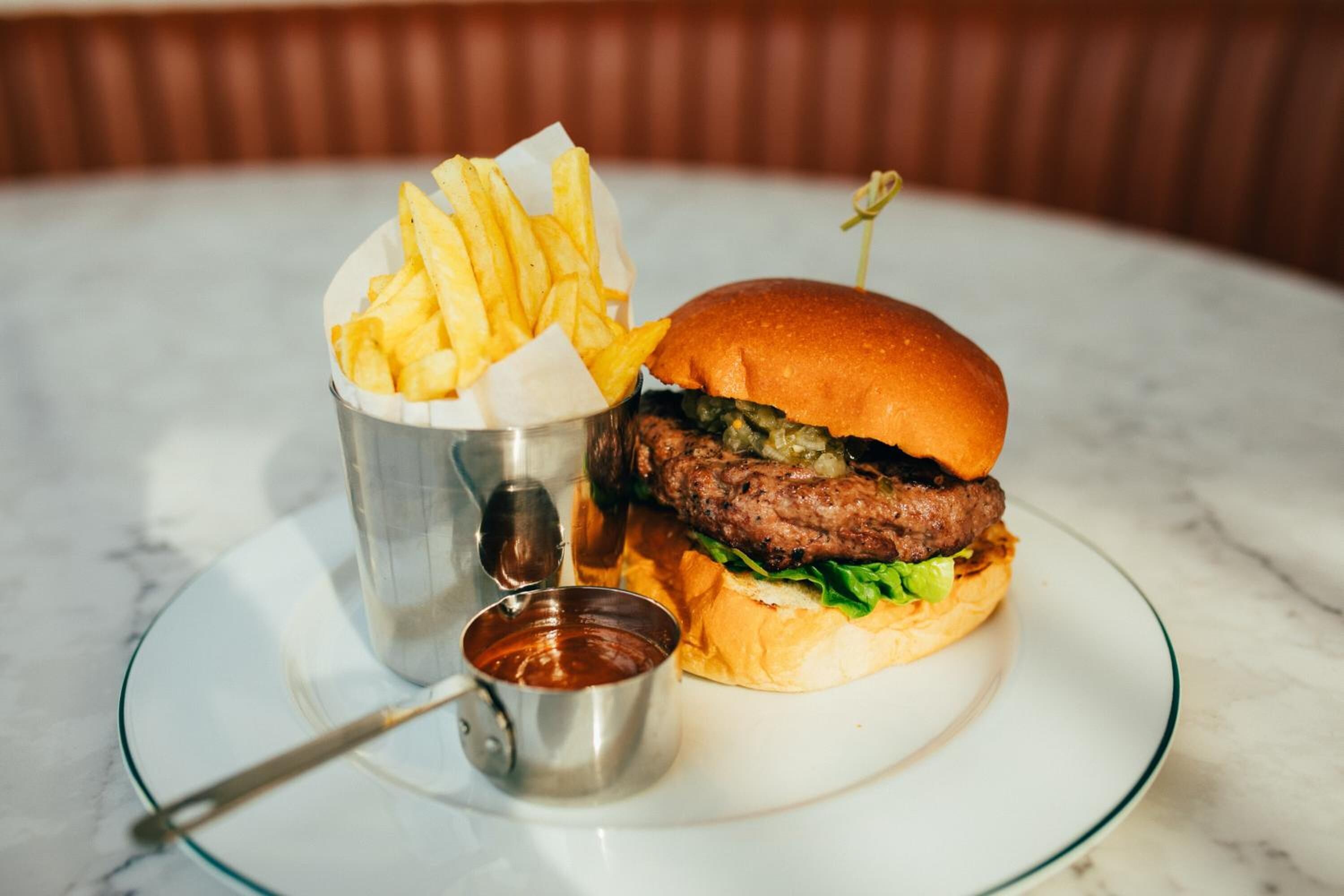 Un hamburger con patatine fritte e ketchup su un piatto di vetro.