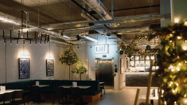 Un restaurante con zona de bar, un árbol de Navidad y un cartel que dice 'Lift'.