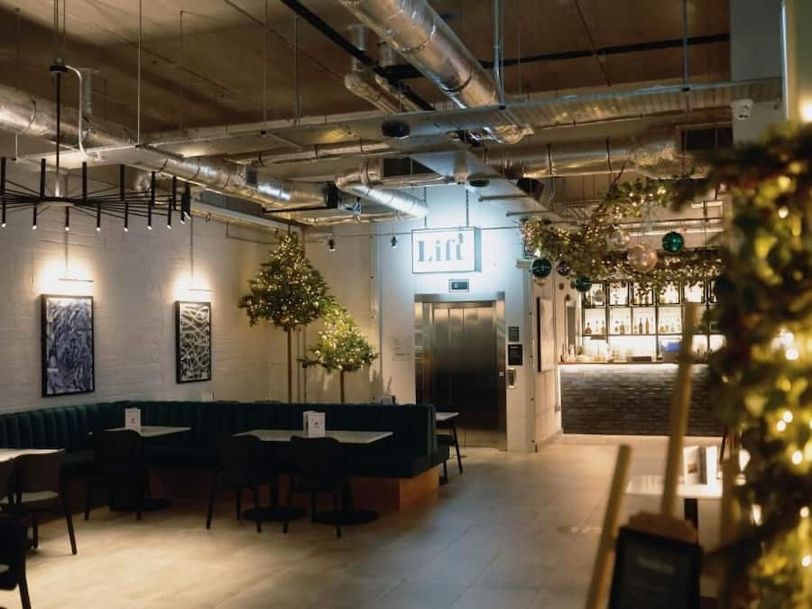 Un ristorante con area bar, un albero di Natale e un cartello con la scritta 'Lift'.